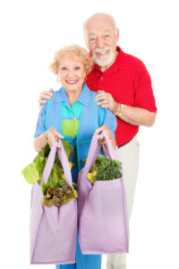 Seniors and Reusable Shopping Bags Senior couple using reusable shopping bags to bring home their groceries. Isolated on white.