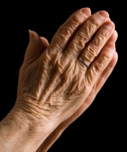 Hands of the old woman on a black background